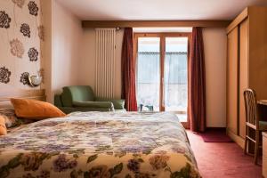 a bedroom with a bed and a chair and a window at Hotel Sonne Sole in Vigo di Fassa