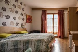 Schlafzimmer mit einem Bett und einem Fenster in der Unterkunft Hotel Sonne Sole in Vigo di Fassa