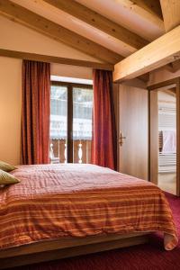 una camera con un grande letto e una grande finestra di Hotel Sonne Sole a Vigo di Fassa