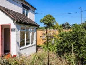 uma pequena casa branca com uma cerca em Hops Cottage em Ashbourne