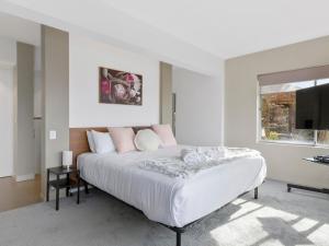 a white bedroom with a large bed and a window at Spectacular Views - 5 Bedroom House and Unit - Free Parking - Free WIFI in Sandy Bay