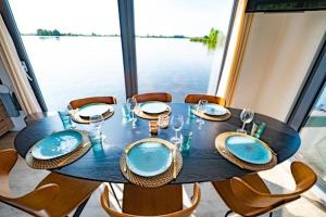 uma mesa de jantar com cadeiras e uma mesa com pratos azuis em Surla houseboat "Aqua Zen" Kagerplassen with tender em Kaag