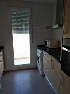 a kitchen with a washer and dryer and a window at Apartamento nuevo en la playa de Piles in Piles