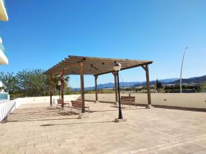 um pavilhão com bancos e luzes num pátio em Apartamento nuevo en la playa de Piles em Piles