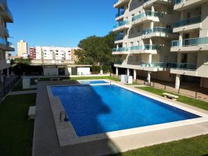 a swimming pool in front of a building at Apartamento nuevo en la playa de Piles in Piles