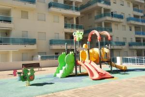 um parque infantil em frente a um edifício de apartamentos em Apartamento nuevo en la playa de Piles em Piles