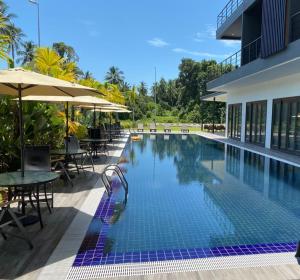 a swimming pool with tables and umbrellas next to a building at MF Roxy Beach Townhouse Sematan Private Unit L31 in Sematan