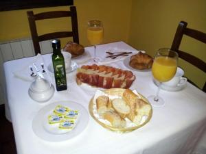 una mesa con un mantel blanco con comida y vasos de zumo de naranja en Casa de Aldea El Frade en Camango