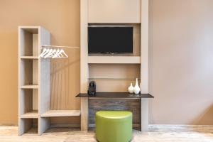 a living room with a tv and a green stool at Select Hotel City Bremen in Bremen