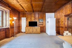 a living room with wooden walls and a tv and a refrigerator at Unterlanpacher Historic Refugium in Laces