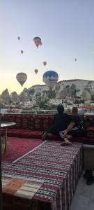 two people sitting on a bench watching hot air balloons at Olivia Cave Hotel in Göreme