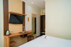 a bedroom with a bed and a tv on a wall at RedDoorz Plus Syariah @ Jalan Dokter Wahidin Bojonegoro in Bojonegoro