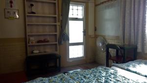 白河區的住宿－Joel's Garden 悠爾庭園古厝民宿，一间卧室配有一张床、一个窗口和一张书桌
