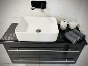 lavabo blanco en una encimera negra en el baño en Évi Vendégház Dunakanyar, en Pilismarót