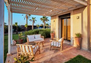a patio with two chairs and a table and a pergola at Marrakech Villa Dar Belkiss in Tameslouht