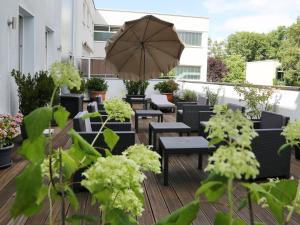 eine Terrasse mit Tischen, Stühlen und einem Sonnenschirm in der Unterkunft Hotel Lindleinsmühle in Würzburg
