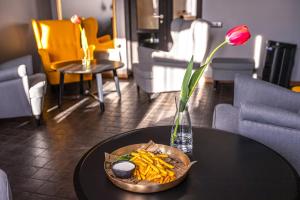 une table avec un bol de frites et un vase avec une fleur dans l'établissement Priedes māja, à Ainaži