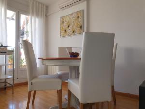 uma sala de jantar com uma mesa e cadeiras brancas em Ático muy luminoso con Parking, em Saragoça