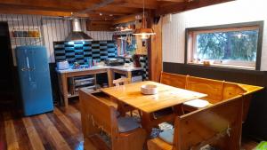 uma cozinha com uma mesa e cadeiras de madeira e um frigorífico em Mapunre em Malalcahuello