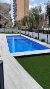 una piscina con agua azul y césped verde en Beach bungalow with swiming pool and long terrace, en San Javier