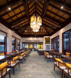 a dining room with tables and chairs and a chandelier at Nghê Prana Hotel & Spa Hoi An in Hoi An