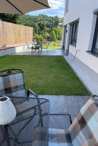 a patio with a table and chairs and a lawn at Apartments Saaldorf-Ferienhaus mit 6 separaten Apartments 45qm-120qm in Bad Lobenstein
