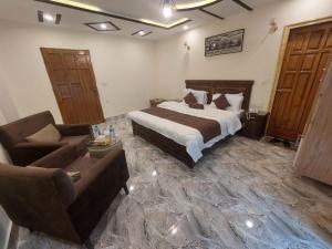 a bedroom with a bed and two chairs and a couch at birmingam palace kalam in Kalām