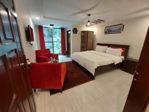 a bedroom with a bed and a red chair at birmingam palace kalam in Kalām