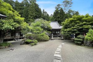 un jardin avec une maison et une rue pavée dans l'établissement 高野山 宿坊 宝城院 -Koyasan Shukubo Hojoin-, à Koyasan
