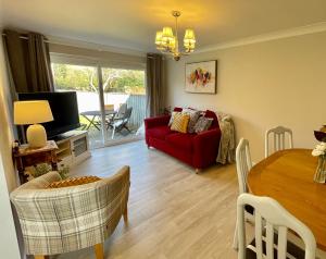 a living room with a red couch and a table at Charming 2 Bedroom Bungalow with open plan living in Felixstowe