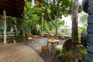 a patio with tables and chairs and trees at The Hammock Goa in Anjuna