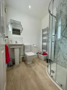 een badkamer met een toilet, een wastafel en een douche bij Charming 2 Bedroom Bungalow with open plan living in Felixstowe