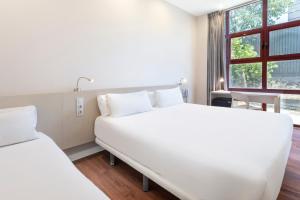 a white bedroom with two beds and a window at B&B HOTEL Madrid Fuenlabrada in Fuenlabrada