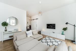 a white living room with a couch and a mirror at Stylish apartment in the heart of Kaunas Old Town in Kaunas