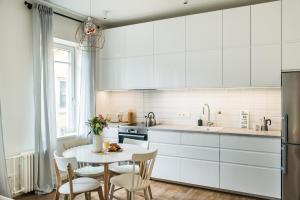 una cucina con armadi bianchi, tavolo e sedie di Stylish apartment in the heart of Kaunas Old Town a Kaunas