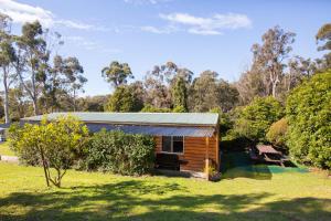 une cabane dans un champ avec des arbres en arrière-plan dans l'établissement Wonboyn Cabins, à Wonboyn