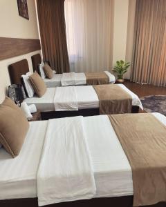 un grupo de 4 camas en una habitación de hotel en Meros Boutique Hotel, en Tashkent