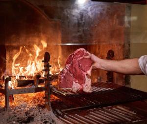 un hombre está sosteniendo un pedazo de carne en una parrilla en Hotel Villa Il Patriarca, en Chiusi