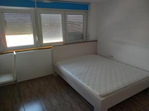 a small bedroom with a bed and two windows at Apartman ROKAN in Daruvar