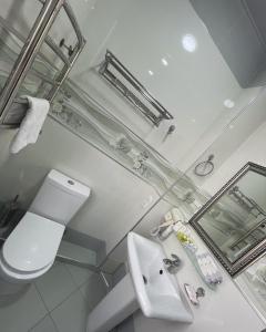 a white bathroom with a toilet and a sink at Meros Boutique Hotel in Tashkent