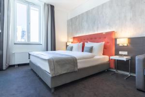 a bedroom with a large bed with an orange headboard at Select Hotel Berlin The Wall in Berlin