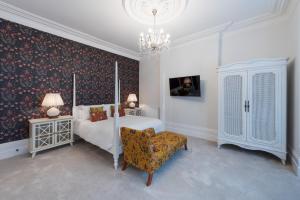 ポーツマスにあるThe Clarence Boutique Roomsのベッドルーム1室(ベッド1台、椅子、シャンデリア付)