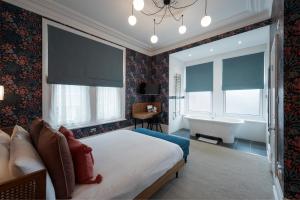 a bedroom with a bed and a bathroom with a tub at The Clarence Boutique Rooms in Portsmouth