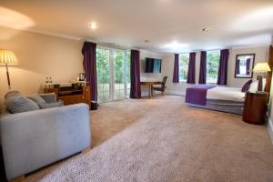 a bedroom with a bed and a couch in a room at Woodland Manor Hotel in Bedford