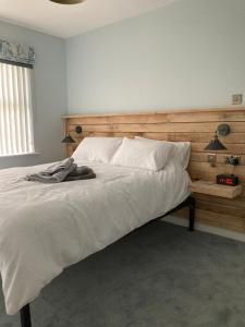 una camera da letto con un grande letto bianco con testiera in legno di Magheraboy Cottage Portrush a Portrush