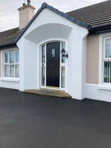 a white house with a black door at Magheraboy Cottage Portrush in Portrush