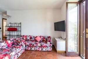a living room with a couch and a tv at Nesso APT with Private Parking & Shared Pool! in Nesso