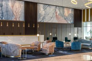 a lobby with chairs and tables and a large painting on the wall at Chrysomare Beach Hotel & Resort in Ayia Napa