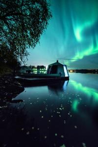 a boat sitting on the water under the northern lights at Aurora Nest – Eco Glass Igloo in Rovaniemi