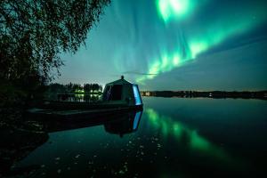 a boat sitting on the water under the aurora at Aurora Nest – Eco Glass Igloo in Rovaniemi